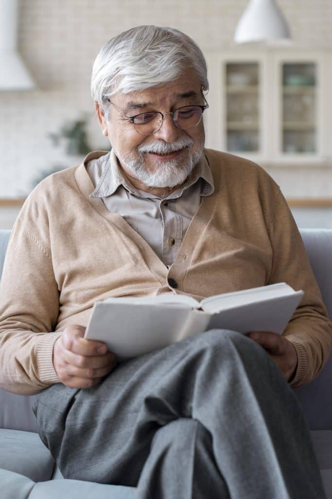 Un homme content dans sa maison en train de lire un livre